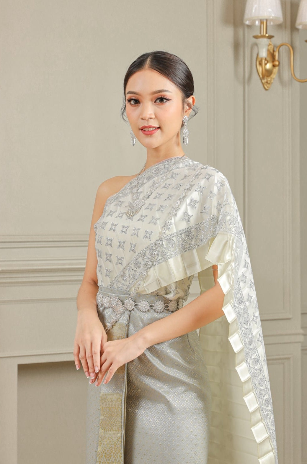 Woman wearing a silver traditional Thai dress to a wedding.