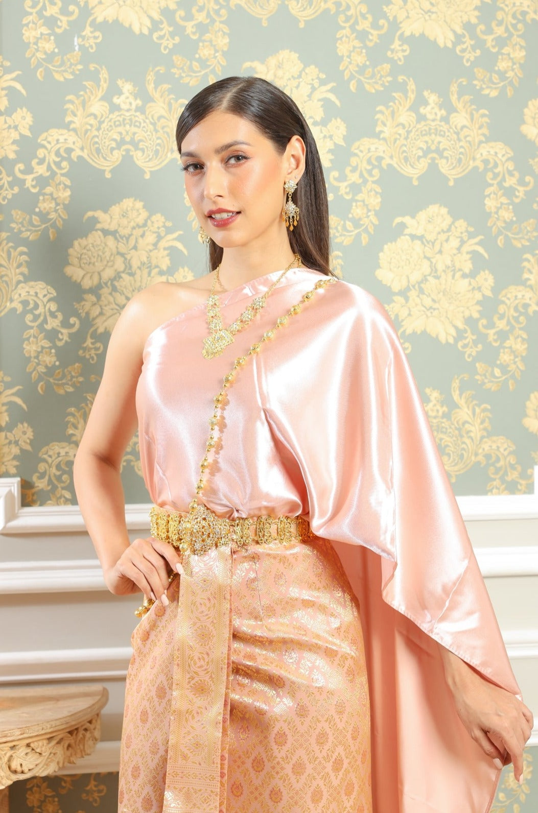 A woman posing in her traditional Thai dress and jewelry.
