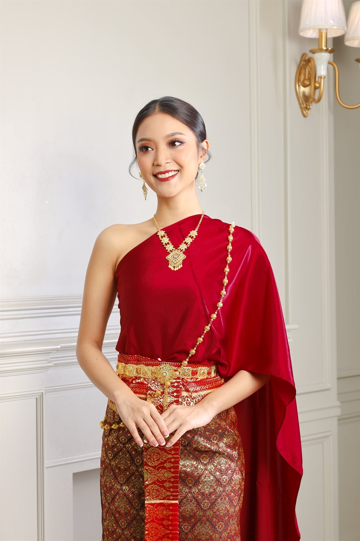 A Thai woman smiles while wearing her traditional Thai dress and jewelry.